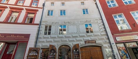 Une vue de rue avec un bâtiment abritant un magasin doté d’une porte en bois et d’une enseigne indiquant « GALERIE D’ART ».