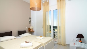 A hotel room with a bed, a small table with a lamp, and a sliding glass door to a balcony. - Iperion Apartment (Rethymno)