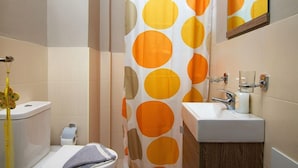 A bathroom with a toilet, sink, and shower curtain with a polka dot pattern. - Iperion Apartment (Rethymno)