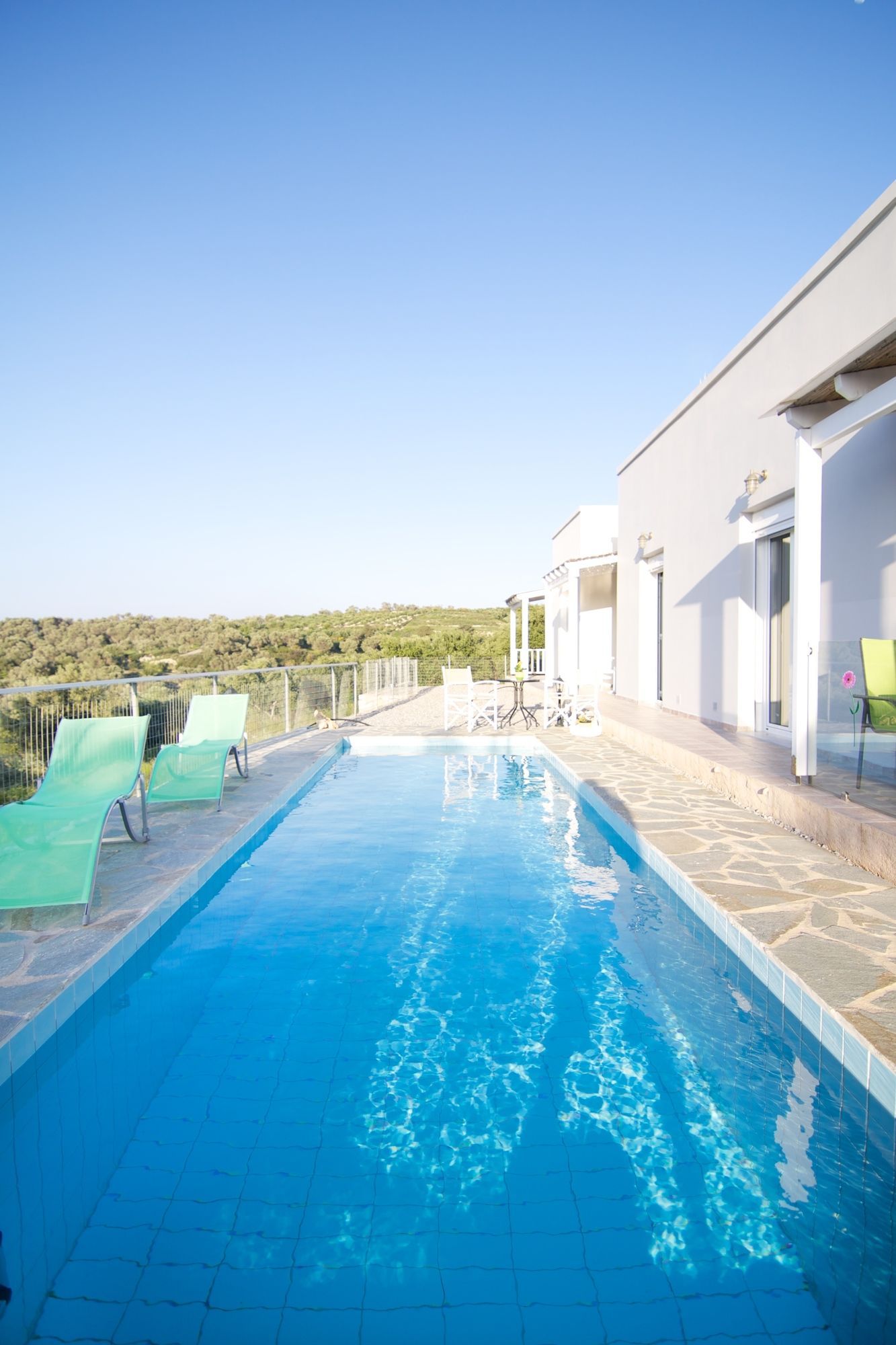 A swimming pool with clear blue water, surrounded by a white building with a balcony.