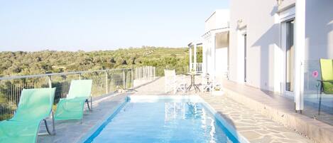 A swimming pool with clear blue water, surrounded by a white building with a balcony.