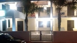 A two-story building with a gated entrance, a parked car, and palm trees. - Bluesky Alloggi (Melendugno)