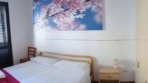 A bedroom with a bed, a nightstand, a chair, a wardrobe, and a wall-mounted painting. - Bluesky Alloggi (Melendugno)
