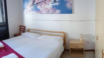 A bedroom with a bed, a nightstand, a chair, a wardrobe, and a wall-mounted painting.