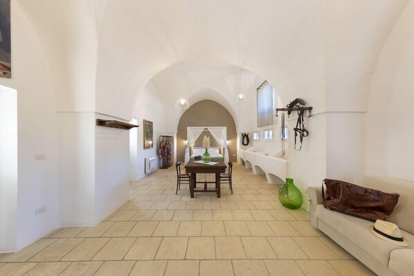 A spacious room with a dining area, a sofa, and a green vase.