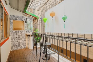 A balcony with a tiled wall, a sink, a chair, and hanging lanterns. - Old Quarter•Train St•2BR• Balcony•247 Check-in (Hà Nội)