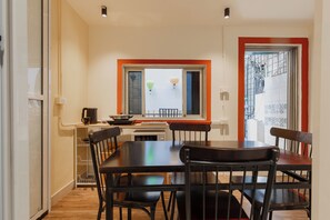 A dining area with a table and chairs, a window with a view, and a kitchen area with a stove and utensils. - Old Quarter•Train St•2BR• Balcony•247 Check-in (Hà Nội)