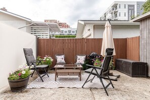 Une terrasse avec des meubles d’extérieur, un barbecue et une clôture en bois.
