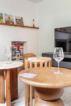 Un salon chaleureux avec une table basse en bois, une chaise assortie également en bois, et un verre à vin posé sur la table.