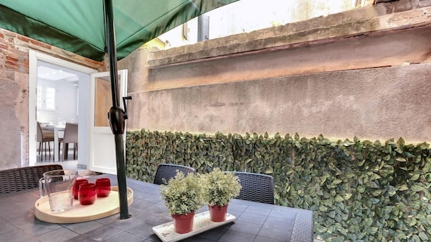 An outdoor patio with a table, chairs, potted plants, and a green canopy. - Pozzo Roverso (Venice)