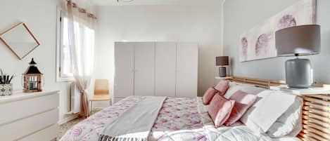 A bedroom with a bed, bedside table, lamp, and artwork on the wall.
