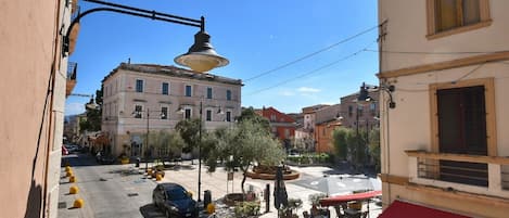 A street view with buildings, outdoor seating, and a parked car.