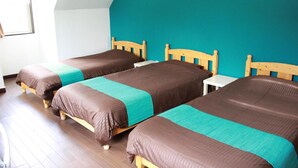 Una habitación con dos camas de madera, una mesa blanca y una pared de acento color aguamarina.