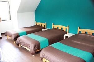 Una habitación con dos camas de madera, una mesa blanca y una pared de acento color aguamarina.