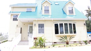 Una casa de dos pisos con techo azul, un porche y un buzón.