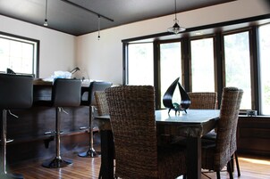 Un comedor moderno con una mesa de madera oscura, sillas de mimbre y una silla negra singular.