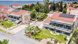 Un hotel con un cartel de 'WELCOME' en el césped, paneles solares en el techo y vistas al mar.