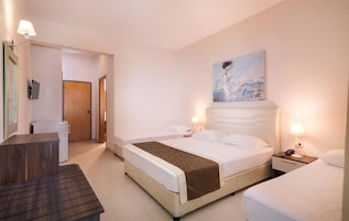 Una habitación de hotel con una cama, mesitas de noche, un escritorio y un cuadro en la pared.