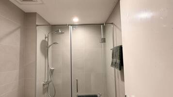 A modern bathroom with a glass-enclosed shower, a toilet, and a bidet.
