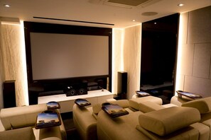 Ein Heimkinozimmer mit großer Leinwand, bequemen Sitzgelegenheiten und einer Stereoanlage.