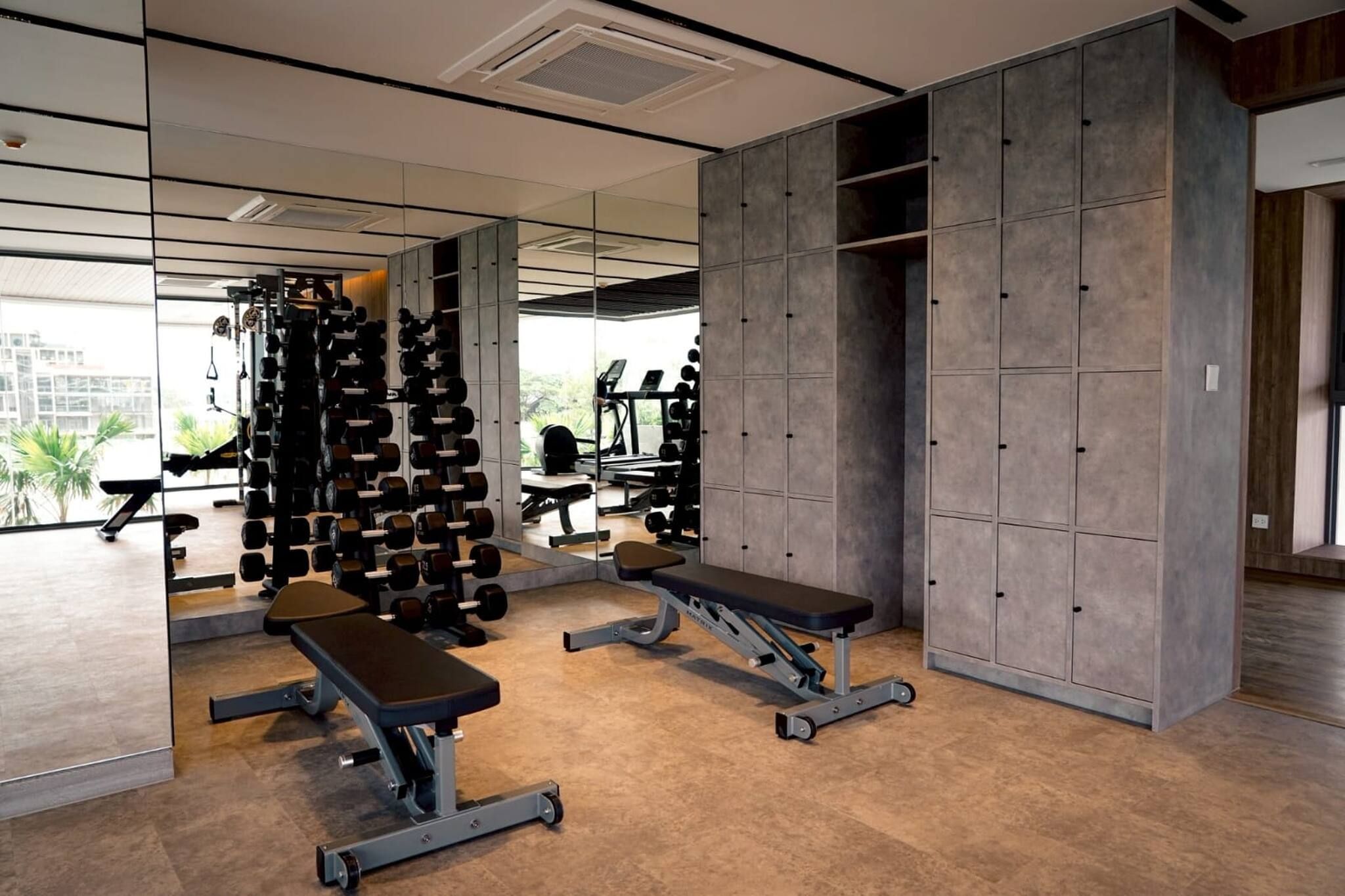 Ein Fitnessstudio mit Krafttrainingsgeräten, Bänken und einer Spiegelwand.