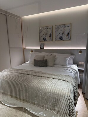 Un dormitorio moderno con una cama grande, una mesita de noche y dos obras de arte colgadas en la pared.