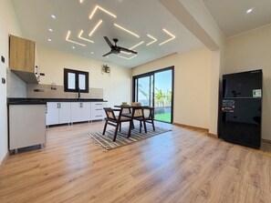 A modern kitchen with a dining area, a ceiling fan, and a black refrigerator. - Private Jacuzzi Escape  Romantic & Luxurious (Cairo Governorate)