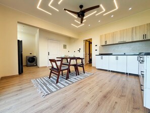A modern kitchen with wooden cabinets, a dining area with a table and chairs, and a ceiling fan. - Private Jacuzzi Escape  Romantic & Luxurious (Cairo Governorate)