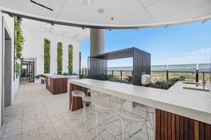 Ein moderner Außenbereich mit Bar, der einen Panoramablick bietet, mit einer langen Theke, Barhocker und vertikalen Bepflanzung.