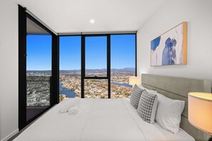Ett hotellrum med en stor säng, utsikt över staden och en tavla på väggen.