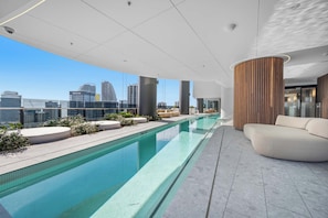 En pool på taket med utsikt över staden, modern arkitektur och en sittgrupp.