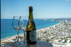 Eine Flasche Minchinery Wein und zwei Gläser auf einem Tisch mit Blick auf eine Küstenstadt.