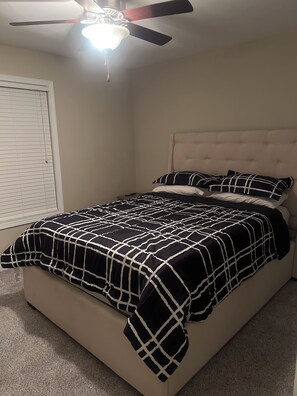 A bedroom with a bed, a ceiling fan, and a window with blinds.
