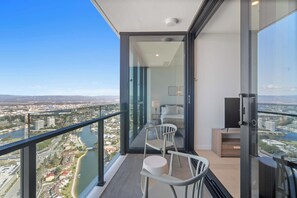 Ein Balkon mit Blick auf die Stadt, ein Bett und ein Fernseher.