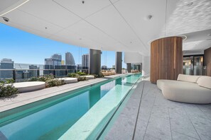 Ein Pool auf dem Dach mit Blick auf die Stadt, moderne Architektur und eine Sitzgelegenheit.