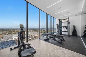 Ein Fitnessstudio mit Blick auf eine Skyline durch große Fenster.