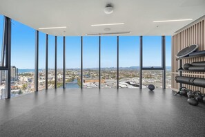 A spacious room with a large window offering a city view, a ceiling with recessed lighting, and a wall-mounted exercise equipment rack. - CASSA CASINO TOWER 2 - Brand New Premium Residence Managed by The Cassa (Broadbeach)