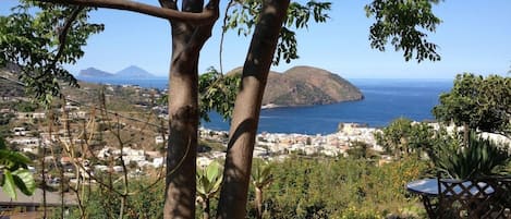Un patio con mesa y sillas, con vista a un pueblo costero y una montaña.
