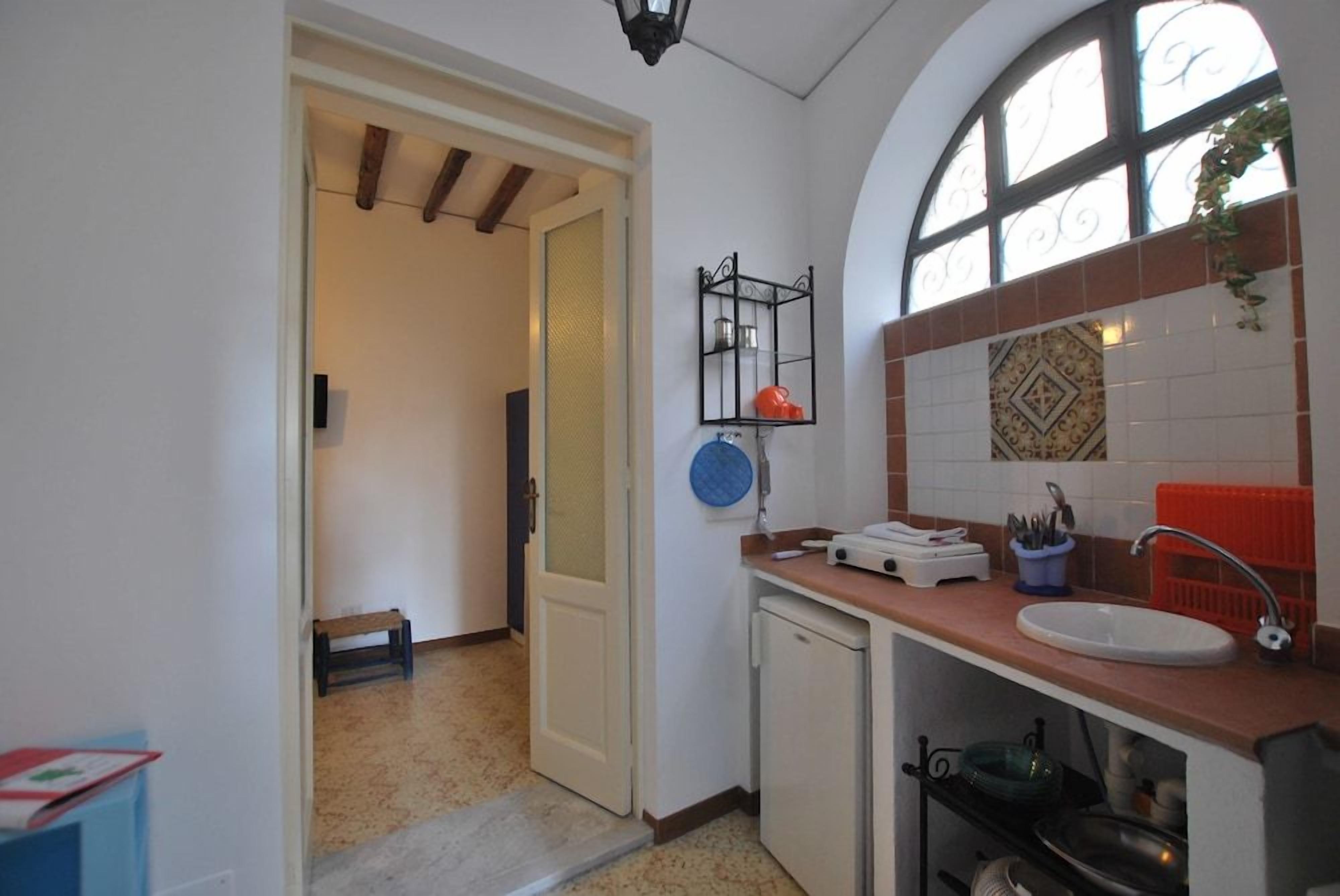 A kitchen with a sink, countertop, and a window with decorative tiles.