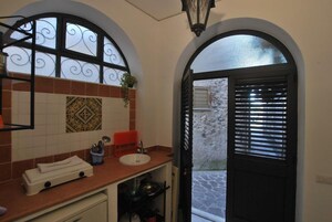 Un baño con pared de azulejos, un lavamanos y una ventana con rejas decorativas.