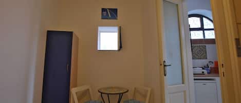 A small room with a dining table and chairs, a cabinet, and a door leading to a kitchen area.