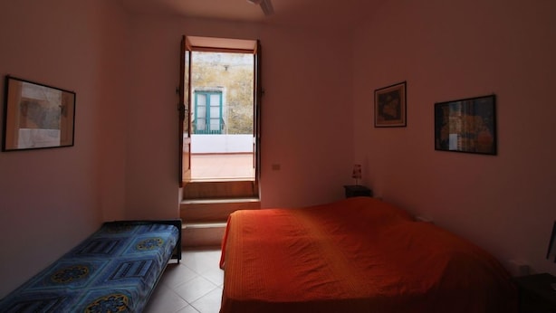 Un dormitorio con una cama individual, una mesita pequeña y un ventilador de techo.