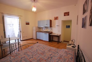 Cocina compacta con comedor, una cama y una pequeña mesa con lámpara.