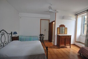 Un dormitorio con cama, mesita de noche, cómoda, ventilador de techo y ventana.