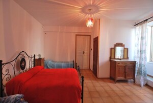 Un dormitorio con cama, cómoda, espejo y puerta que da a otra habitación.