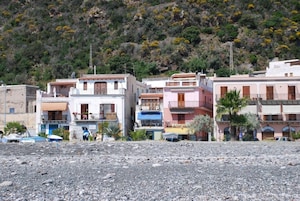 Zona costera con edificios, terreno rocoso y vegetación.