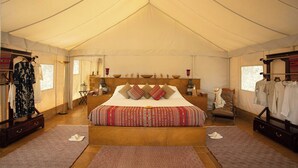 Quarto com tenda, uma cama grande, uma cadeira e um guarda-roupa.
