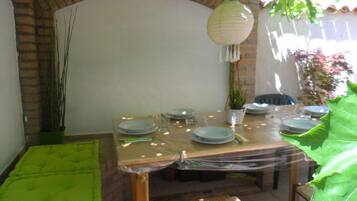 Een eetruimte met een tafel voor vier personen, omringd door bakstenen muren en potplanten.