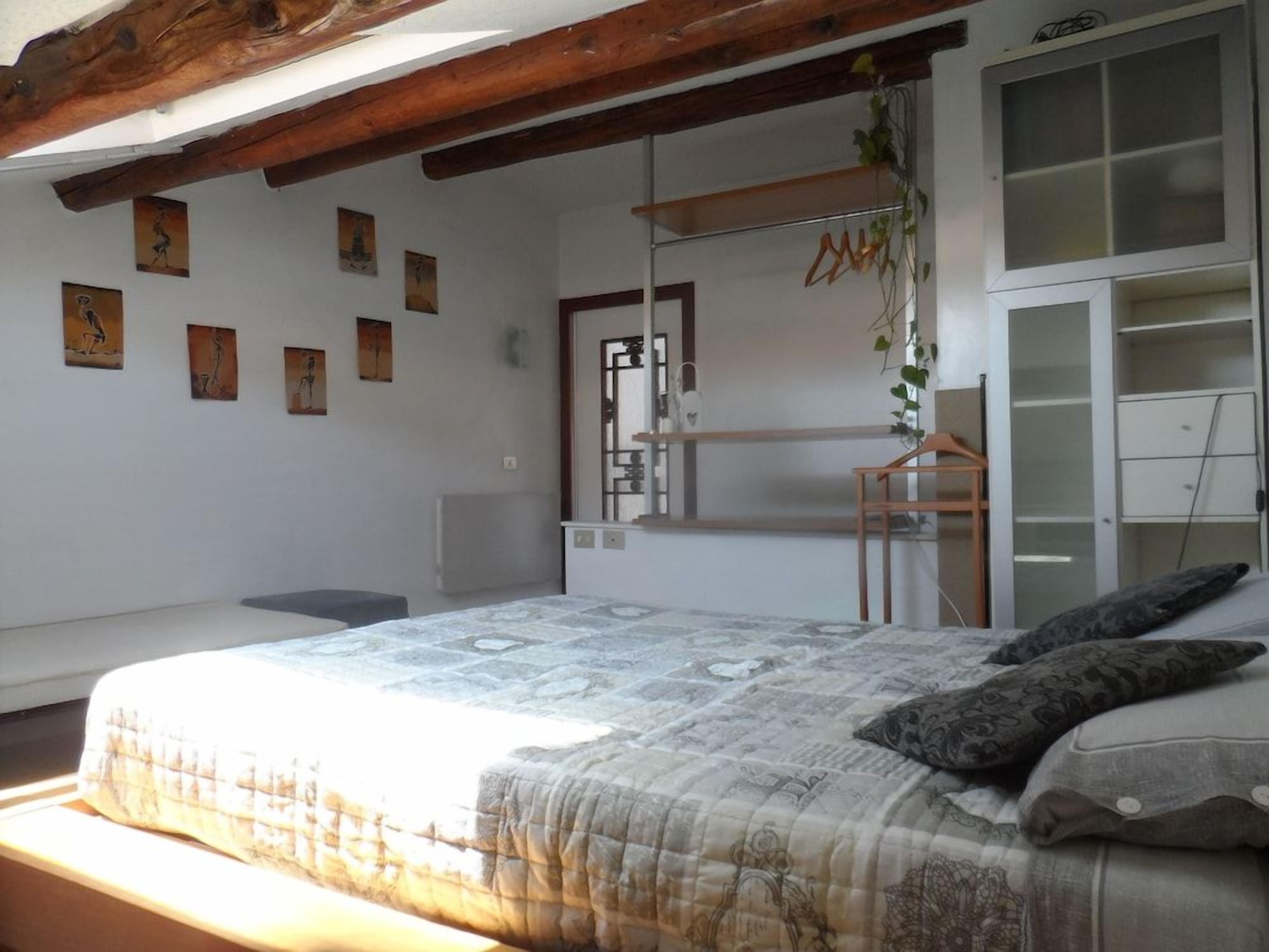 Een slaapkamer met een bed, een kledingkast en een wandplank met spullen eraan.