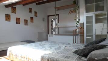 Een slaapkamer met een bed, een kledingkast en een wandplank met spullen eraan.